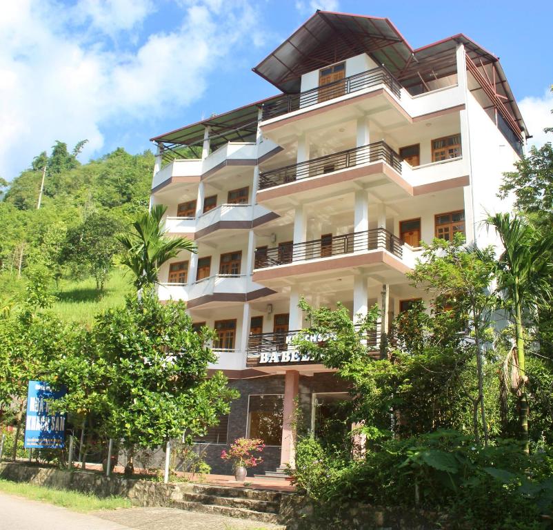 a tall white building with trees in front of it at Ba Be Legend Hotel in Ba Be18