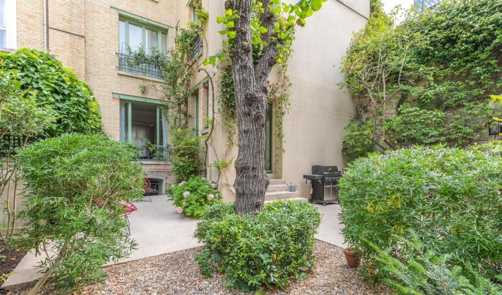 un patio con un árbol frente a un edificio en La Villa d'Auteuil, en París