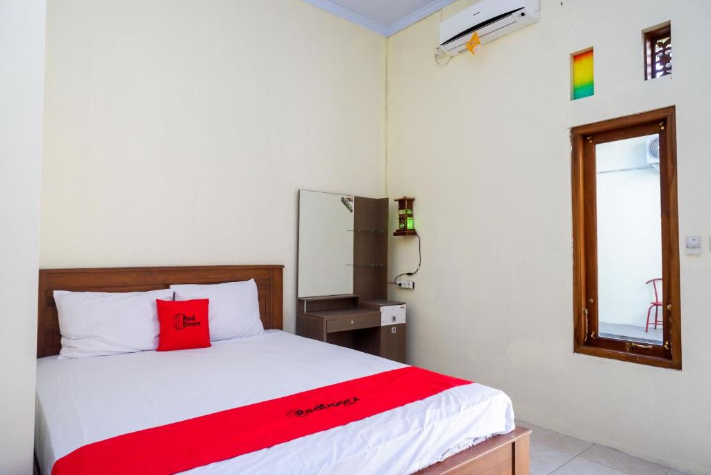 a bedroom with a red pillow on a bed at RedDoorz @ Umbul Ponggok Waterpark Klaten in Klaten