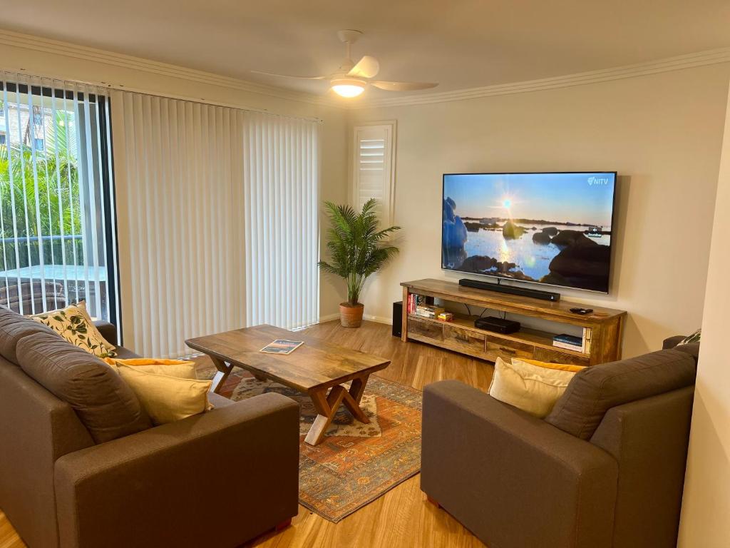 a living room with two couches and a flat screen tv at Millenium 101 in Forster