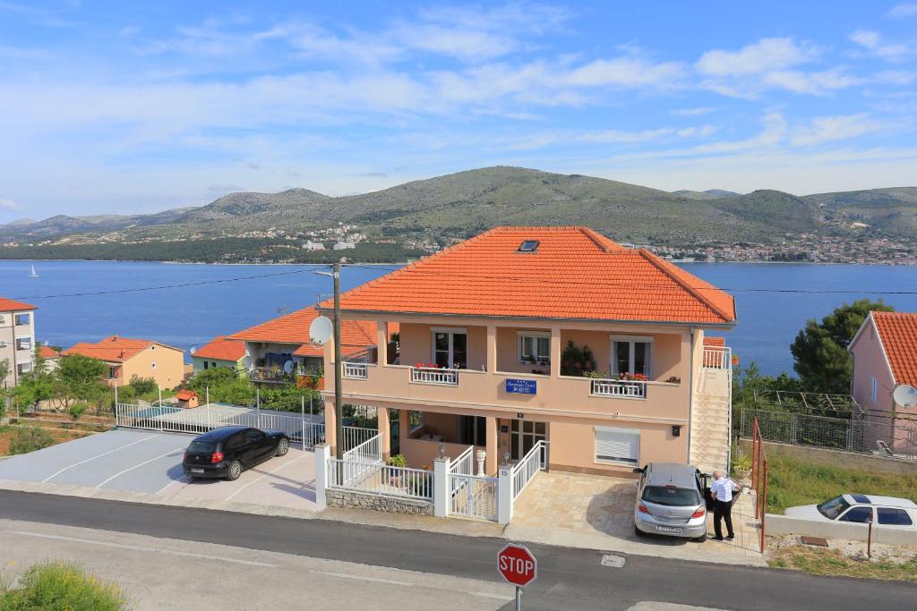 a house with an orange roof with a view of the water at Apartments with a parking space Okrug Donji, Ciovo - 18796 in Okrug Gornji