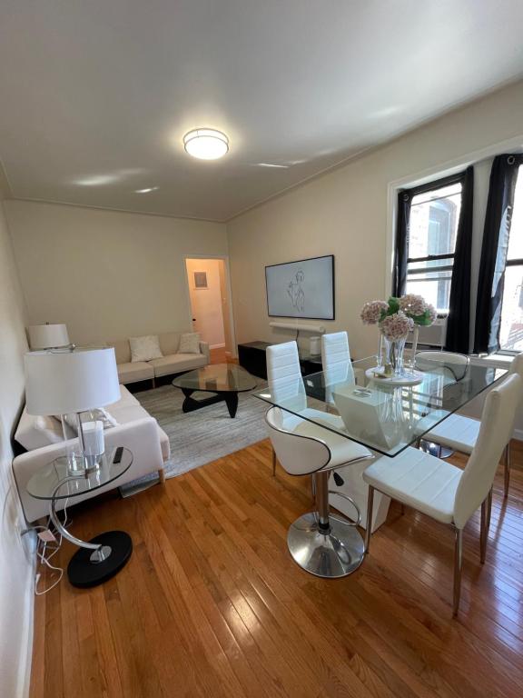 a living room with a glass table and white chairs at 1BR Apt in Sunnyside 15 min to Manhattan in Woodside