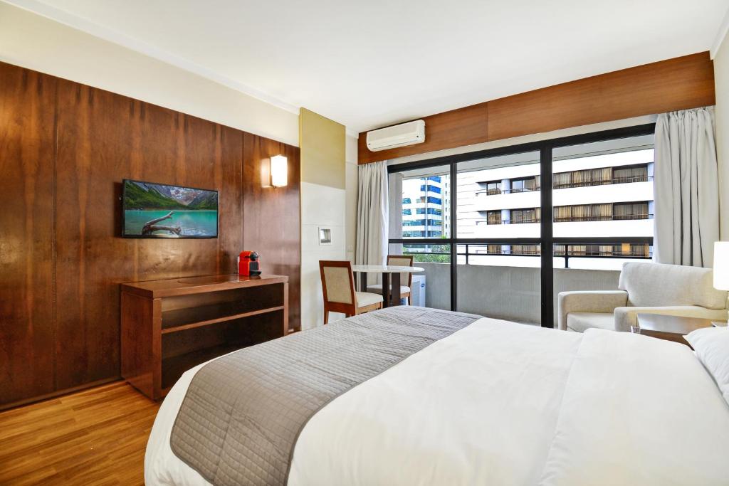 um quarto de hotel com uma cama e uma grande janela em Suite at the Grand Plaza Avenida Paulista em São Paulo