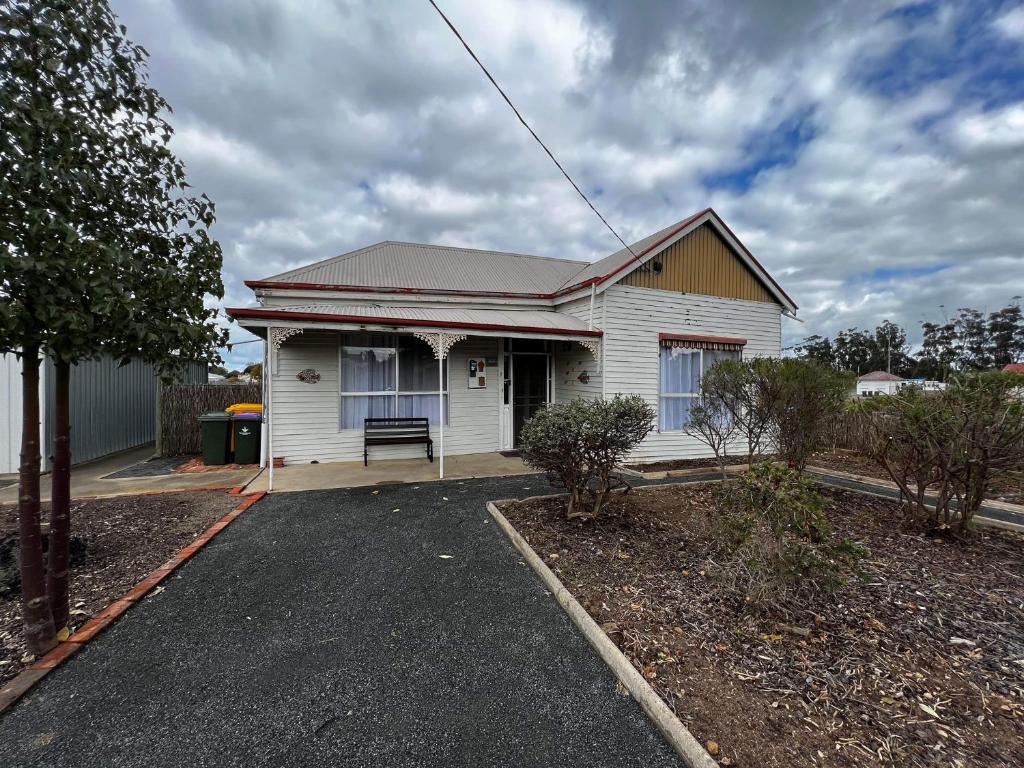 a white house with a bench in front of it at The Crooked Cottage in Murtoa