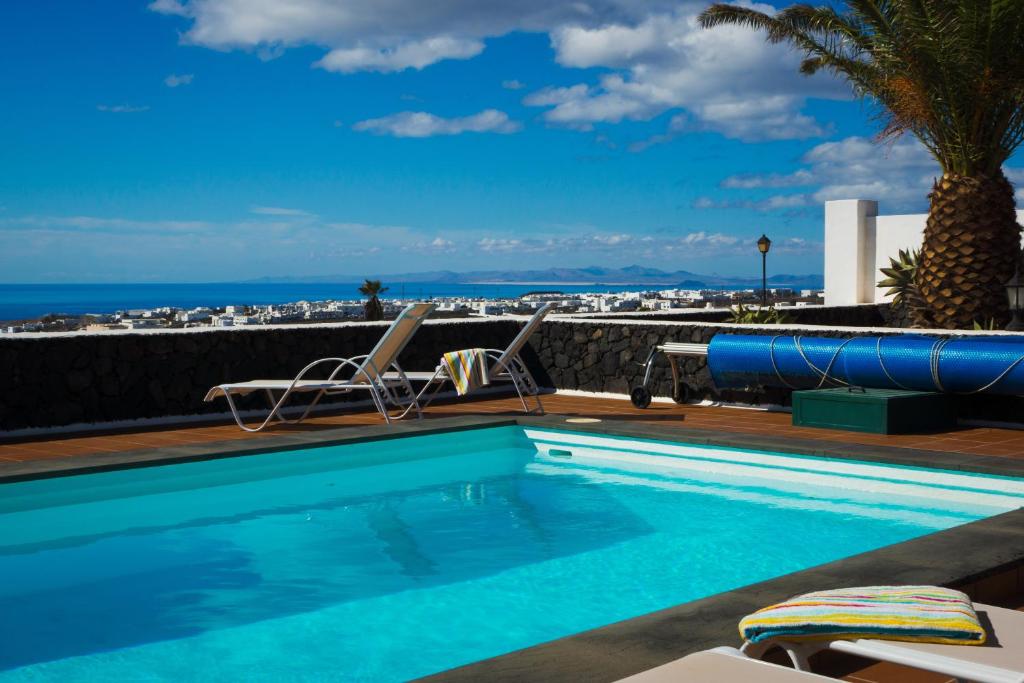 una piscina con sillas y el océano en el fondo en Casa Villa La Vega en Tías