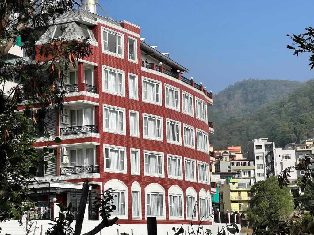 a red building with white windows and a mountain at Terrakotta Rishikesh in Rishīkesh