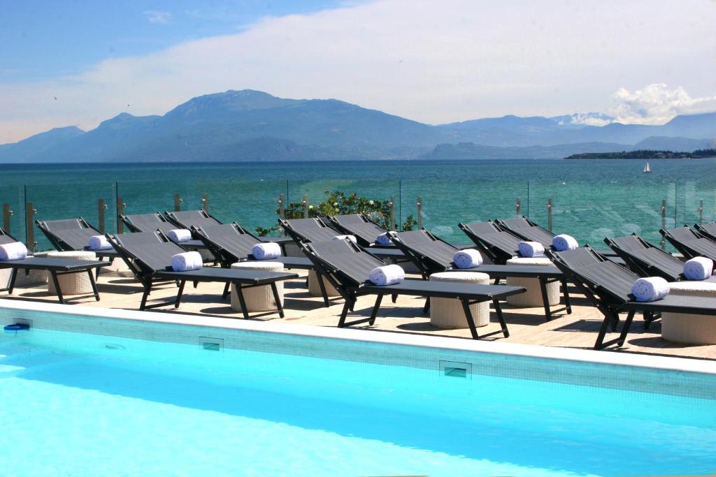 eine Reihe von Liegestühlen neben einem Pool in der Unterkunft Park Hotel in Desenzano del Garda