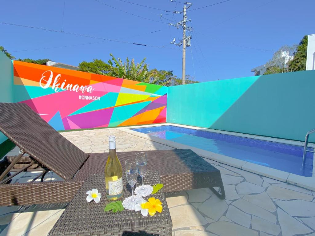 a table with a bottle of wine next to a pool at グランディオーソ沖縄プールヴィラ恩納4 in Onna