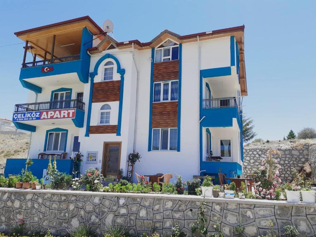 a blue and white building with a stone wall at Salda Gölü Çeliköz Apart in Yeşilova