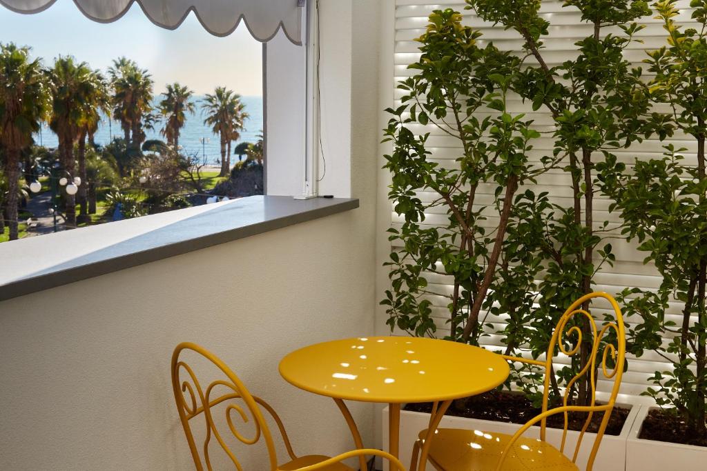 un tavolo giallo e sedie di fronte a una finestra di Attico Fronte Mare Residenza Matilde a Chiavari