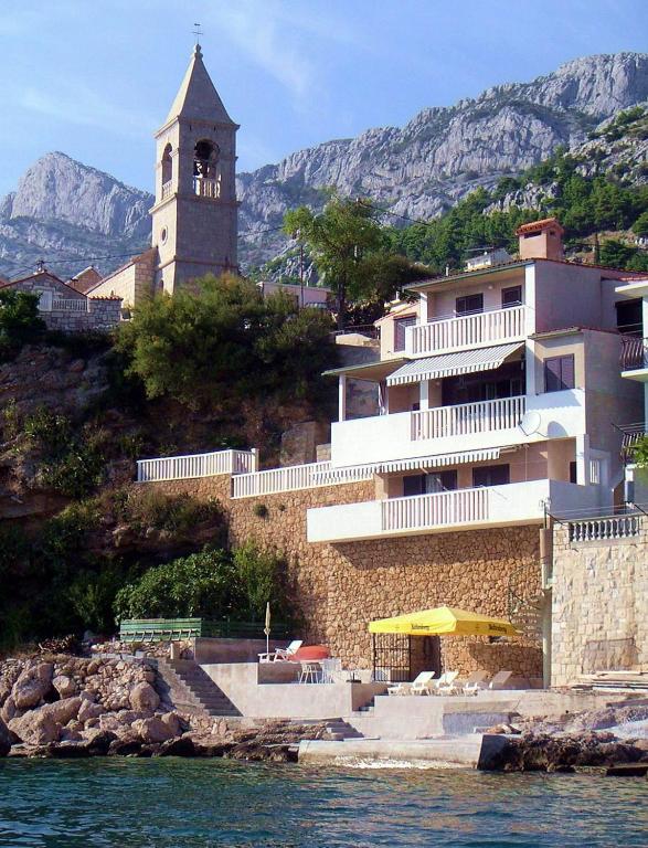 a building with a clock tower on a hill next to the water at Apartments by the sea Pisak, Omis - 1018 in Pisak