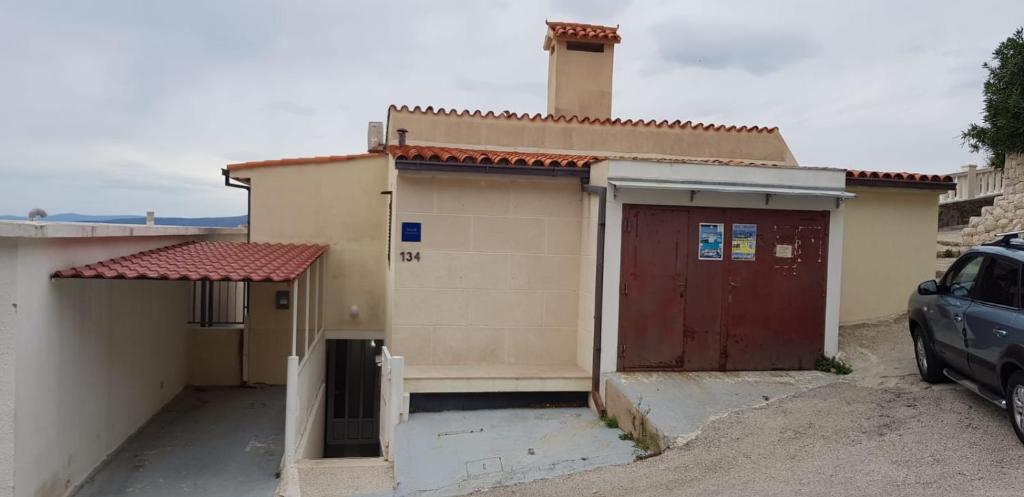 a small house with a red door and a garage at Apartments by the sea Pisak, Omis - 1018 in Pisak