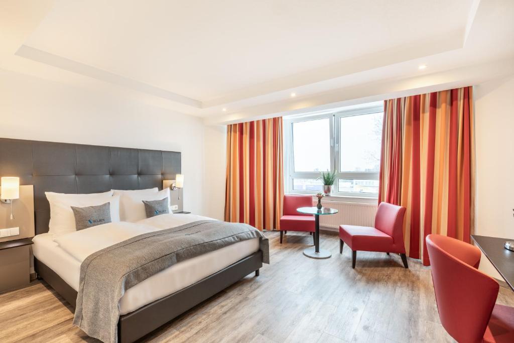 Pokój hotelowy z łóżkiem, biurkiem i krzesłami w obiekcie Select Hotel A1 Bremen-Stuhr w mieście Stuhr