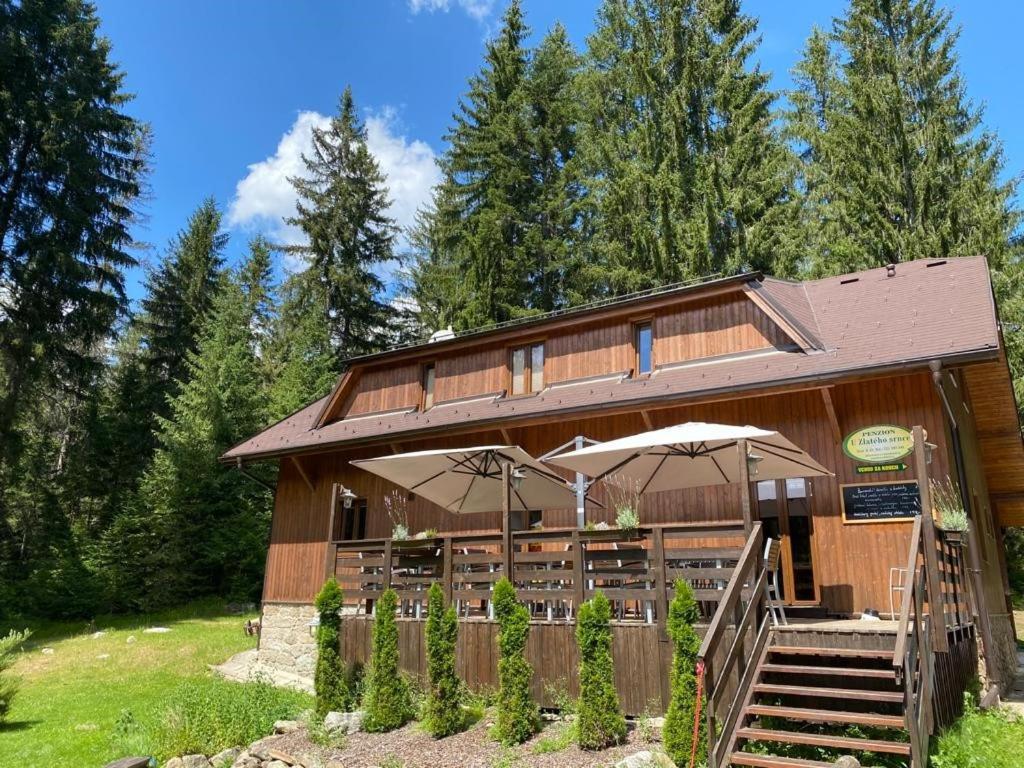 a wooden building with umbrellas in front of it at Penzion U Zlatého srnce in Srní