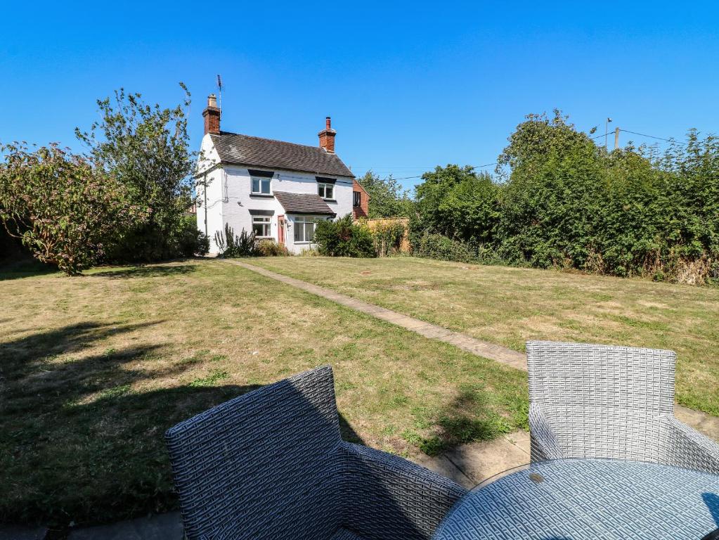 a house with two chairs in front of a yard at Hops Cottage in Ashbourne