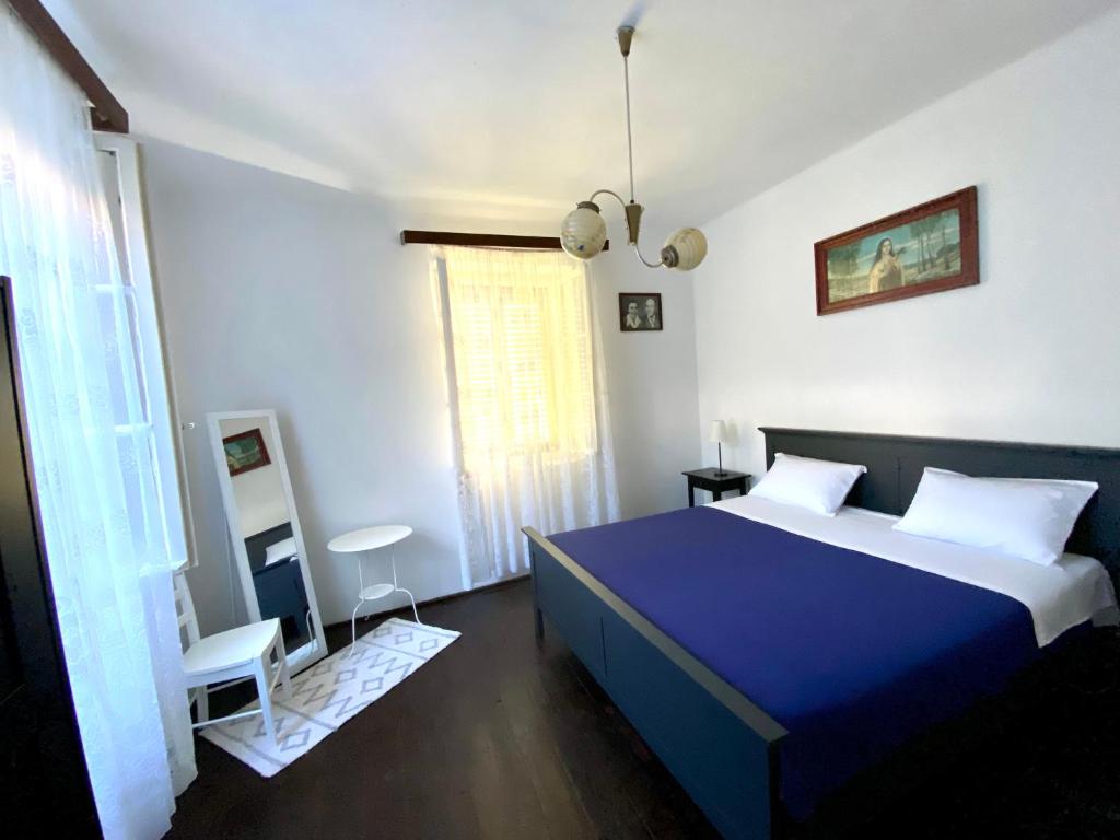 een slaapkamer met een blauw bed en witte muren bij Family house Bacalja in Preko