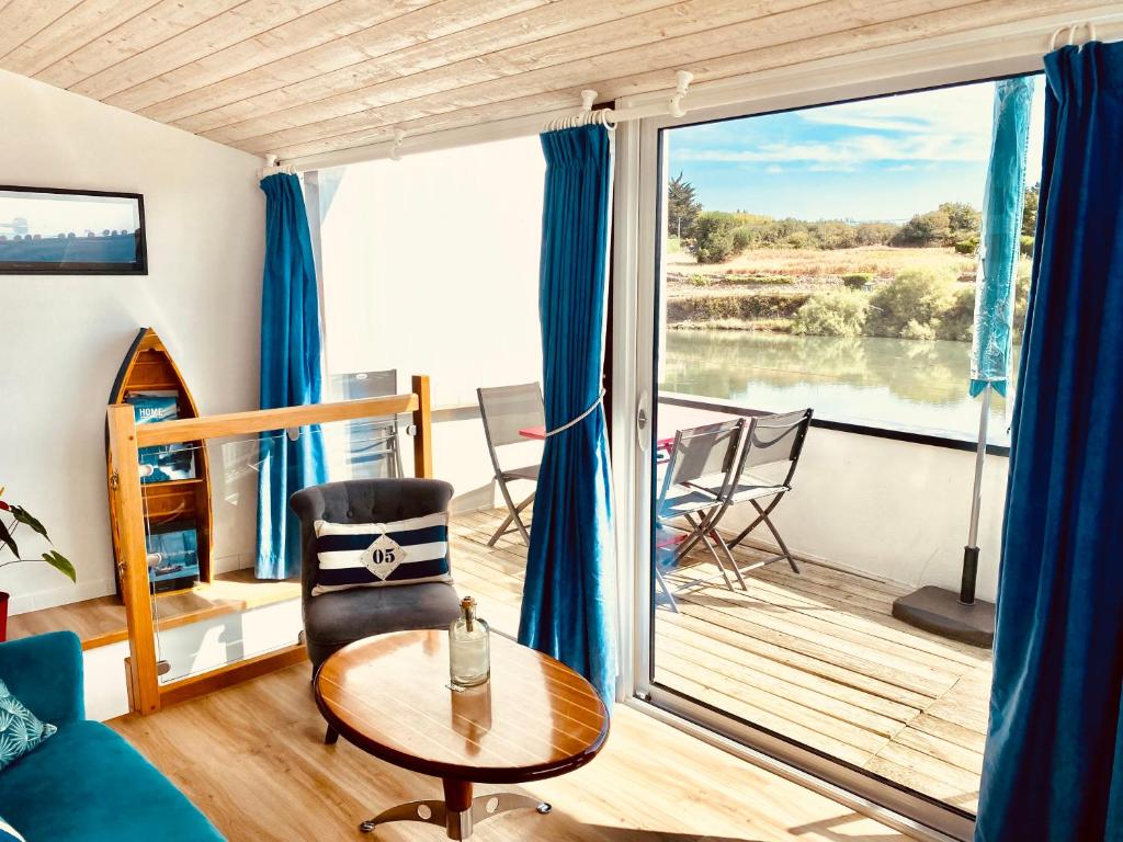 ein Wohnzimmer mit einem Tisch und einem großen Fenster in der Unterkunft Maison avec terrasse vue sur ria d'Etel - moulin du Sac'h in Étel