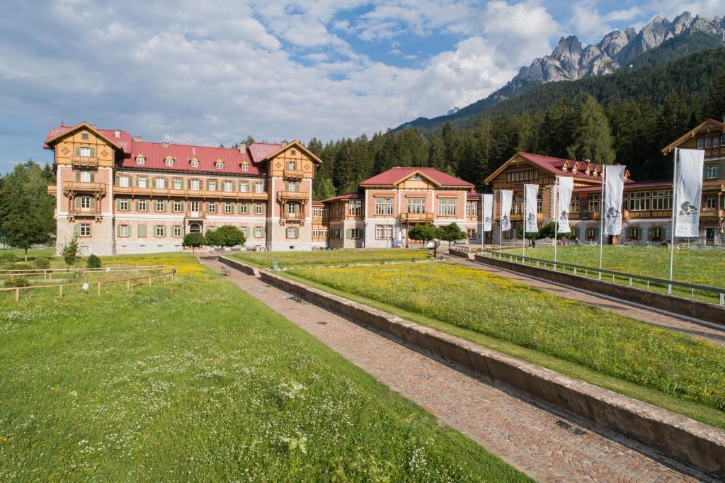 ein großes Gebäude mit einem Grasfeld davor in der Unterkunft Guesthouse - Cultural Center Gustav Mahler in Toblach