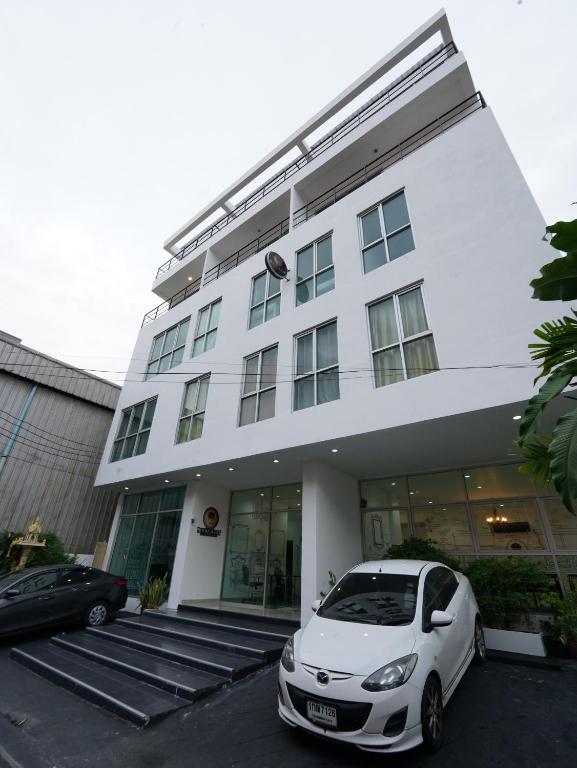 un coche blanco estacionado frente a un edificio en RoomQuest Bangkok Sukhumvit 50 en Amphoe Phra Khanong