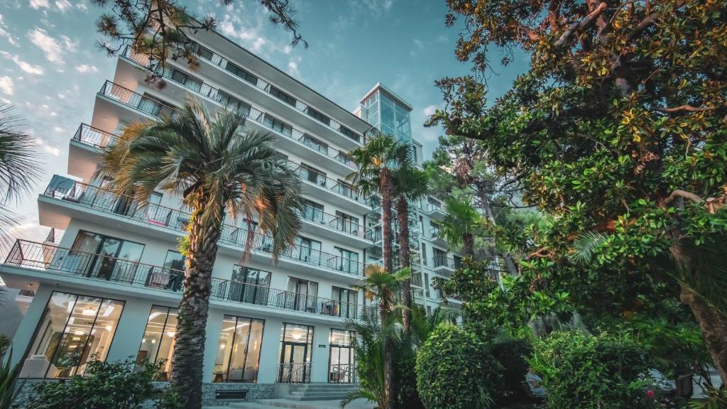 a building with palm trees in front of it at Парк СПА Отель Нарт in Gagra