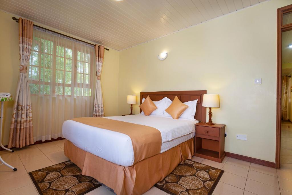 a bedroom with a large bed and a window at The Cycads Suites in Nairobi