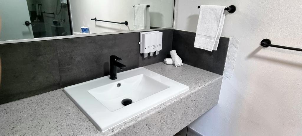 ein weißes Waschbecken im Bad mit Spiegel in der Unterkunft Y Motels Gympie in Gympie