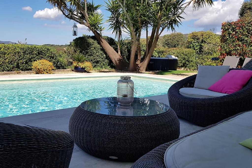 un patio con sillas de mimbre y una mesa junto a la piscina en Rez de Villa, vue magnifique, piscine chauffée privée, spa en Sainte-Maxime