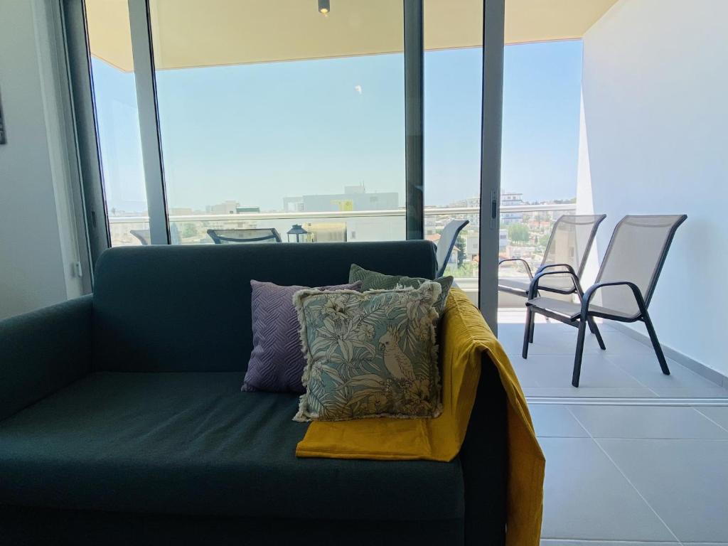 a couch with pillows on it in a room with windows at Silver Line 1-Bedroom Apartment in Larnaca in Larnaca