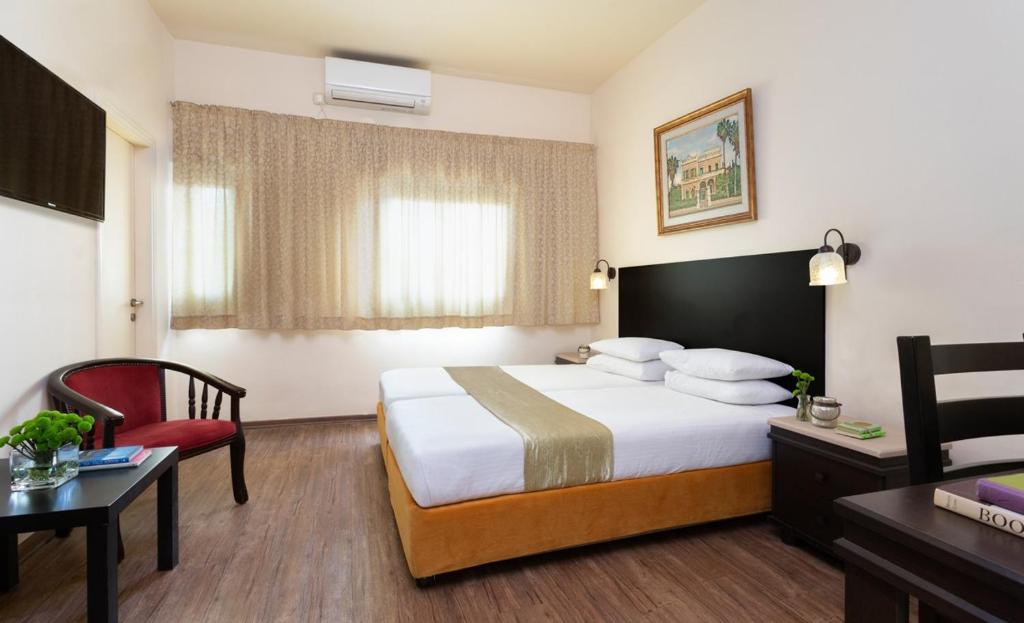 a hotel room with a bed and a red chair at A Little House In Rechavia in Jerusalem
