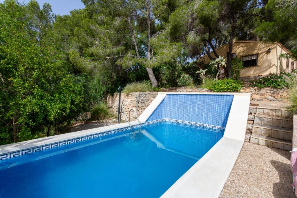 Una piscina azul con árboles al fondo. en Las Pedrizas, en Pilar de la Horadada