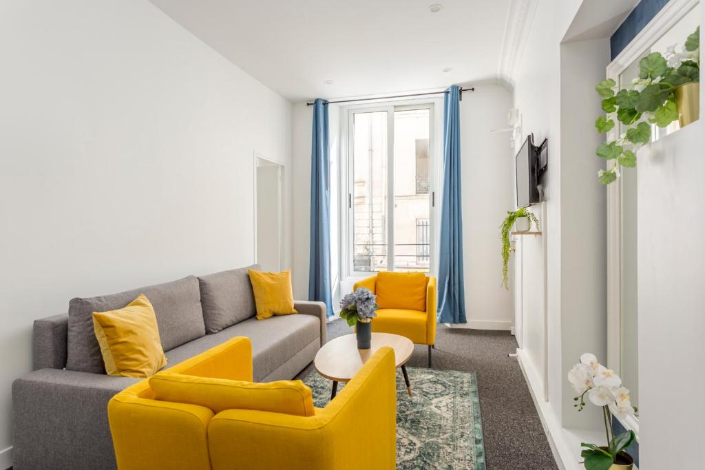 salon z szarą kanapą i żółtymi krzesłami w obiekcie Cosy 2 bedrooms apartment with bathrooms - Louvre w Paryżu
