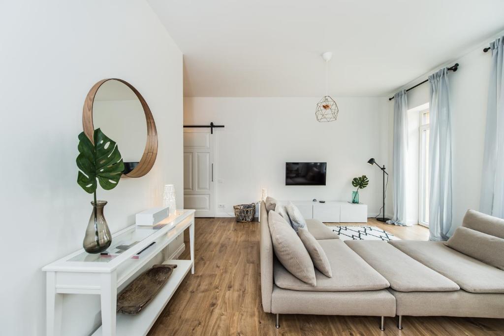 a white living room with a couch and a mirror at Stylish apartment in the heart of Kaunas Old Town in Kaunas