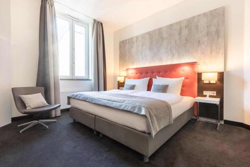 a bedroom with a large bed and a chair at Select Hotel Berlin The Wall in Berlin