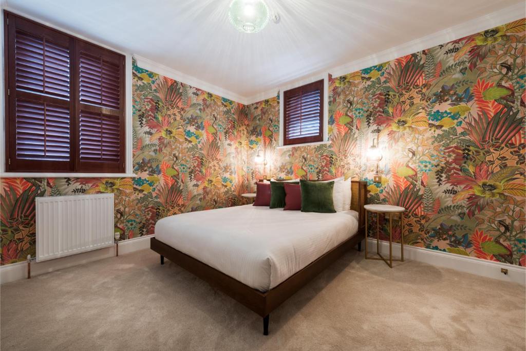 Dormitorio con cama con papel pintado colorido en The Clarence Boutique Rooms, en Portsmouth