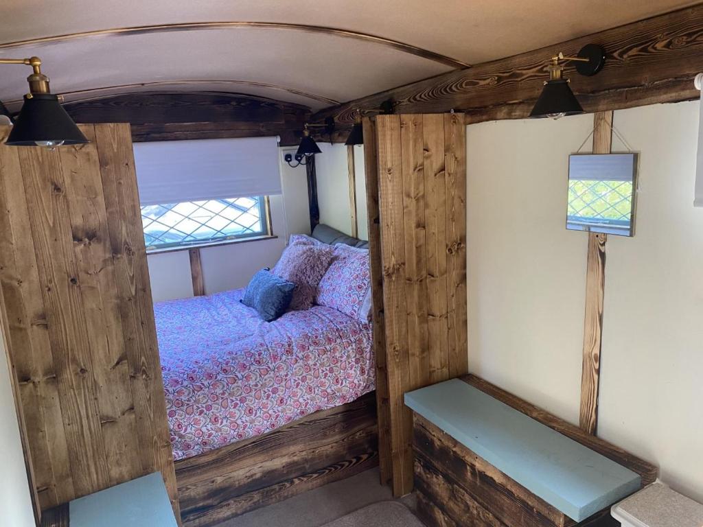 a small bedroom with a bed in a wooden room at Modern Shepherd's Hut at St Anne's in Plymouth