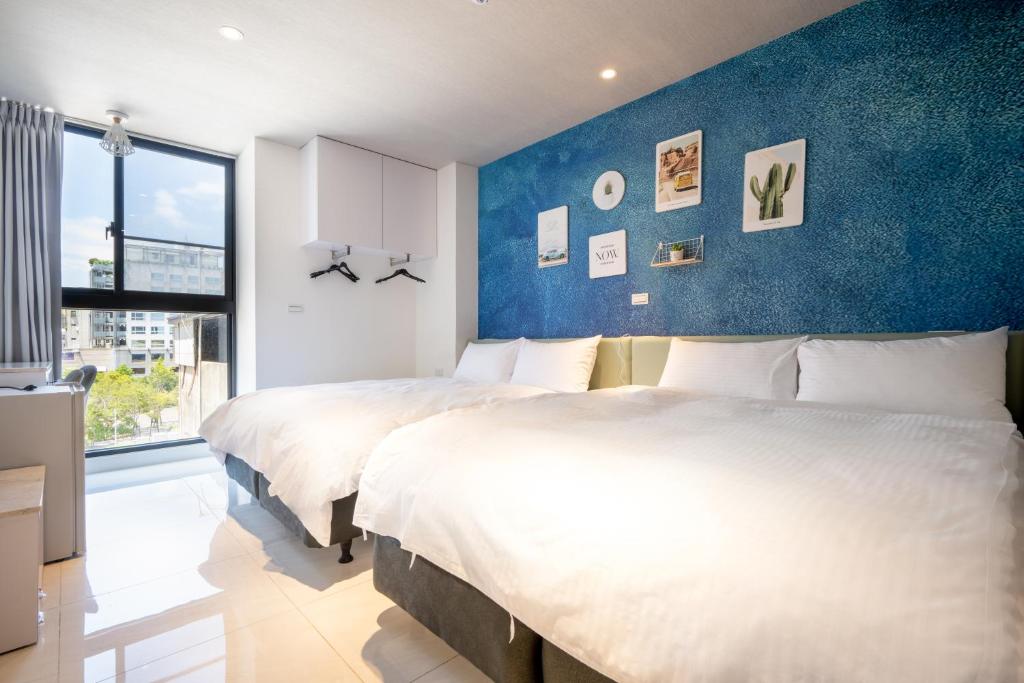 2 Betten in einem Schlafzimmer mit blauer Wand in der Unterkunft Harmony Hostel in Tainan