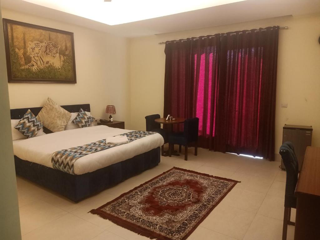 een hotelkamer met een bed en een tafel en gordijnen bij HOTEL THE AM BLISS in Gurgaon