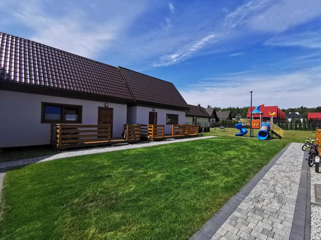 een huis met een tuin met een speeltuin bij NADMORSKI RESORT in Niechorze