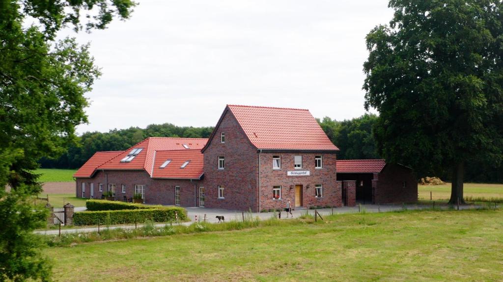 twee bakstenen gebouwen met rode daken in een veld bij Gitstapper Hof in Wassenberg