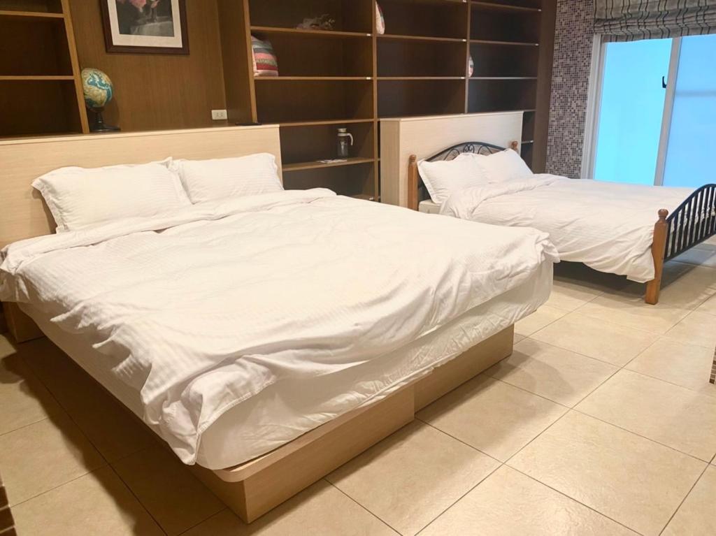 two beds with white sheets in a room at Er Jie's House in Tainan