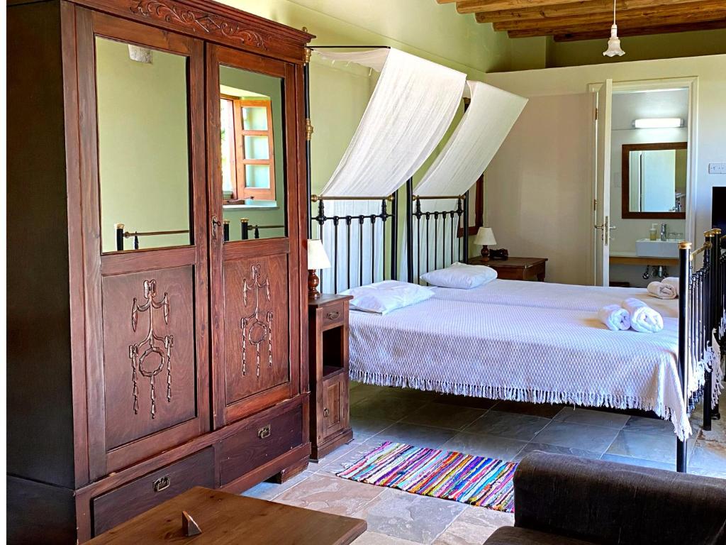 a bedroom with a bed and a large wooden cabinet at Eveleos Country House in Tochni