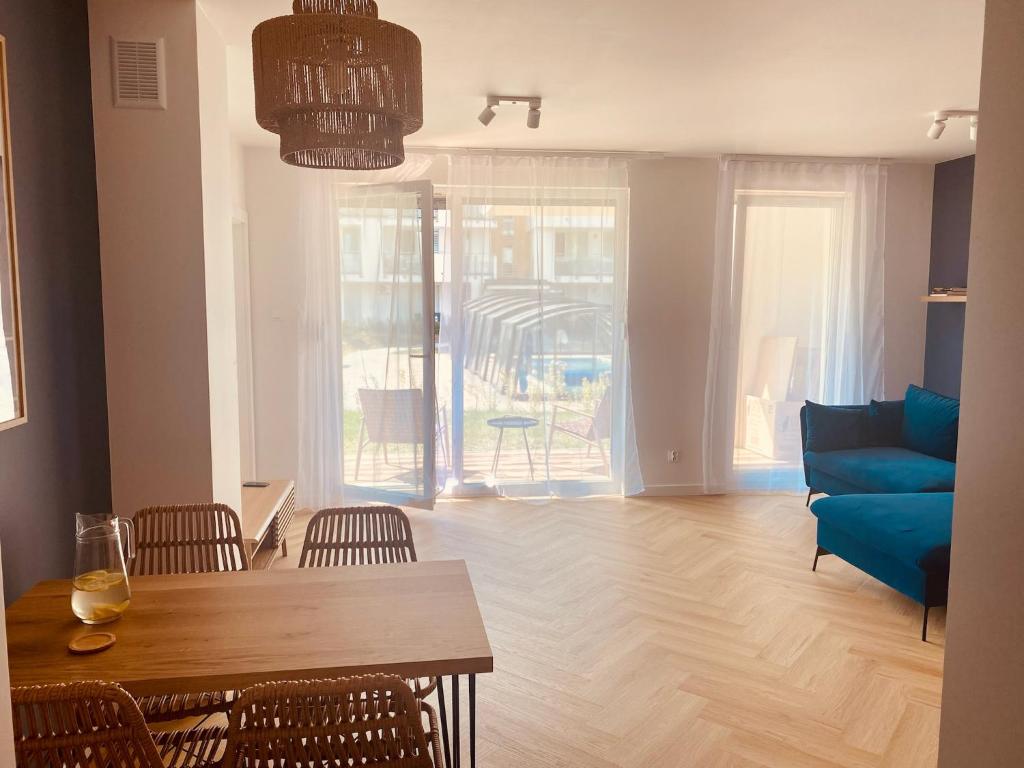 a living room with a table and a blue couch at Apartament Family Premium - Baltic Sun Sztutowo in Sztutowo