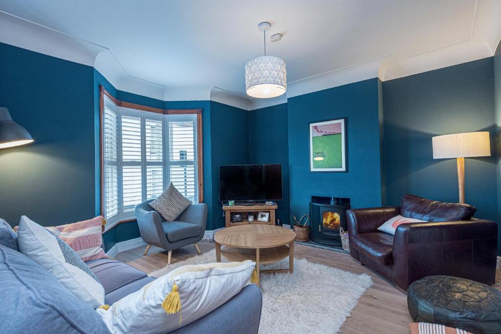 a blue living room with a couch and a table at Beautiful Redbrick Home in Ruthin Centre & Parking in Ruthin