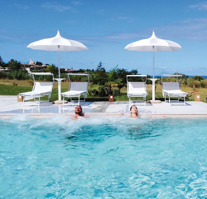 two people in a swimming pool with chairs and umbrellas at Il Borghetto Resort & Spa in Tropea
