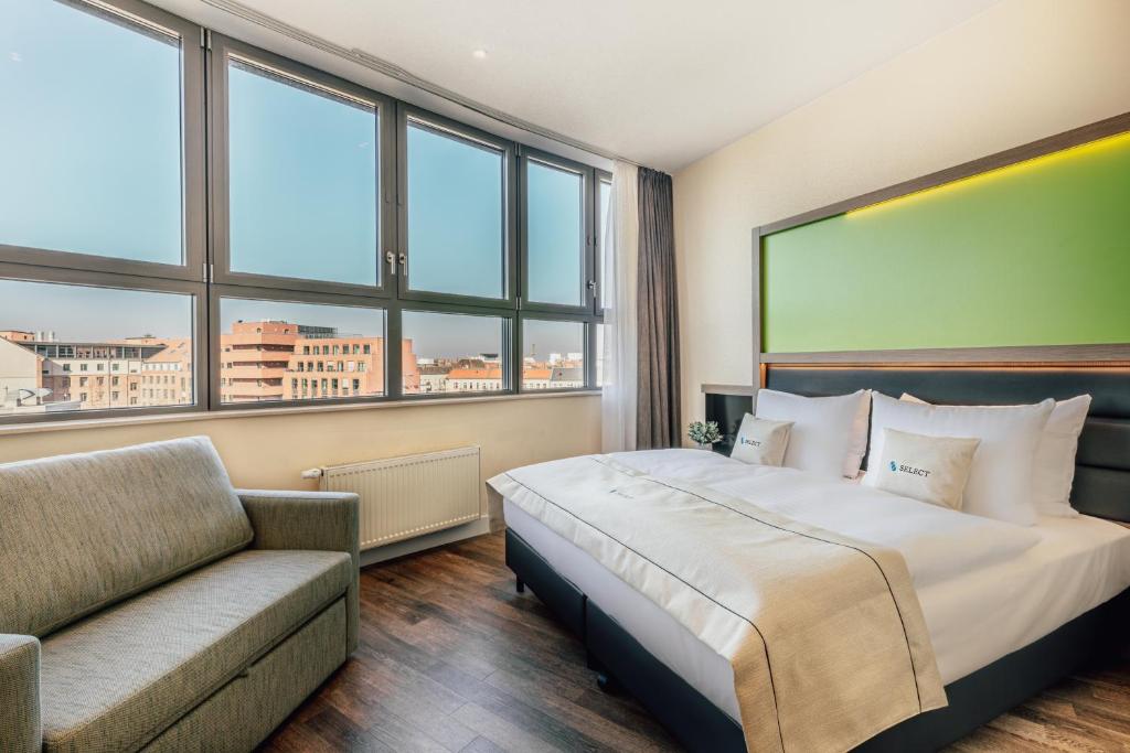 a bedroom with a bed and a couch and windows at Select Hotel Style Berlin in Berlin