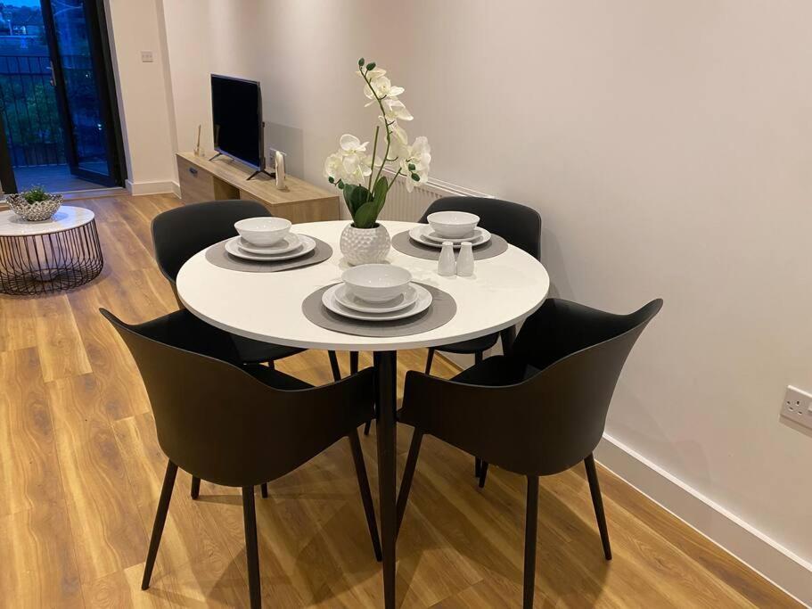 a dining room table with chairs and a white table at Triple t homes Cosy 2 bedroom Apartment with balcony in Ilford
