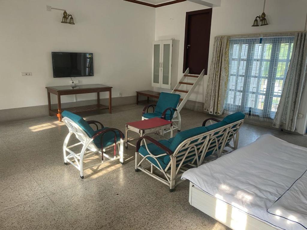 Habitación con sillas, cama y TV. en BNL FARMHOUSE, en Dhanbād