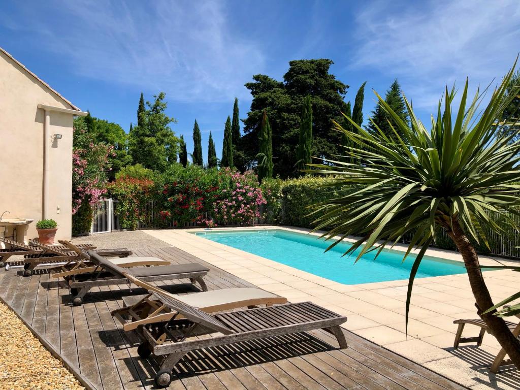 a swimming pool with lounge chairs and a palm tree at La Bri...Gite in L&#39;Isle-sur-la-Sorgue