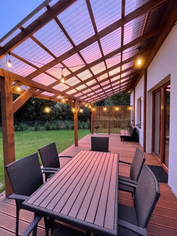 una terraza de madera con mesa y sillas de madera en Dom całoroczny nad jeziorem Brajnickim 