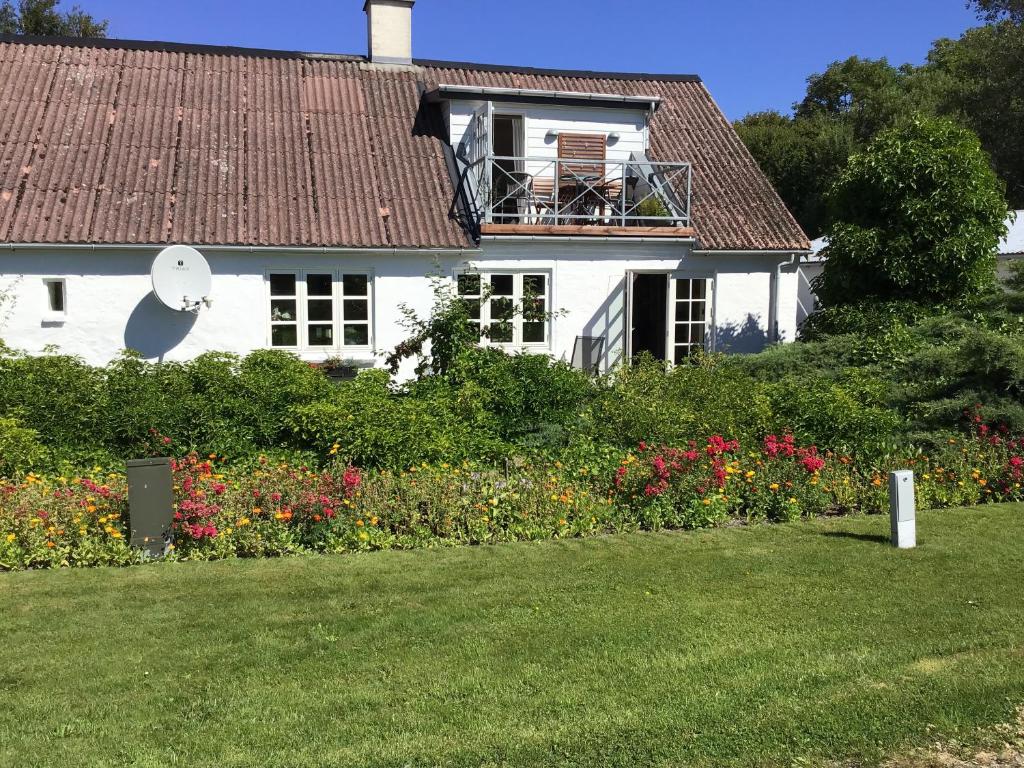 a white house with a balcony and flowers at Vejlen Bed & Kitchen in Vadum